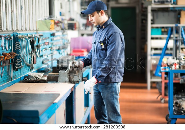 Worker securing a metal\
plate in a vise