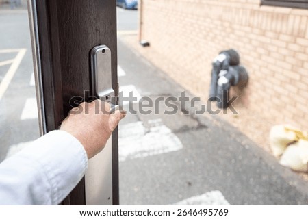 Worker seen opening a fire exit door within a typical NHS hospital in Britain. Notice the zebra crossing which extends to a carpark.