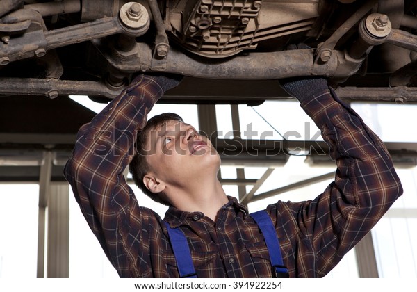 Worker of service station repairing car. Man\
repairing car