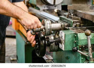 The Worker Sets The Size Of The Feed On The Dial On The Lathe.