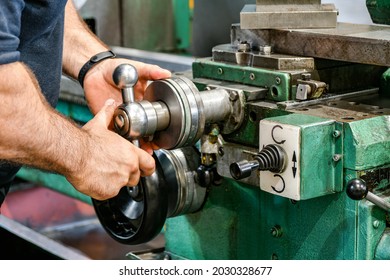 The Worker Sets The Size Of The Feed On The Dial On The Lathe.