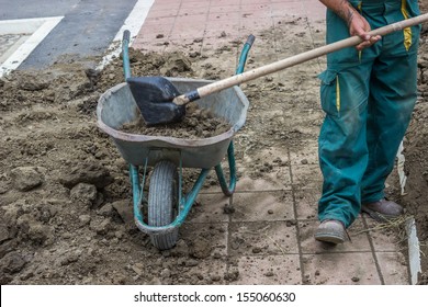 A Worker Shovels Dirt Into A Wheelbarrow at a residential construction site doing preparation for lawns