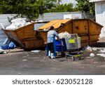 worker shoving trolley with garbage  throw in the  yellow truck can.