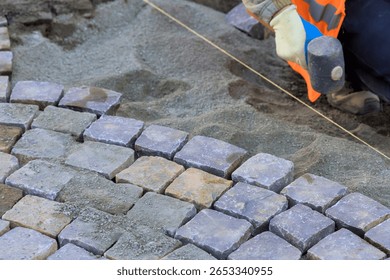 Worker skillfully positions cobblestones while ensuring alignment for new pathway construction