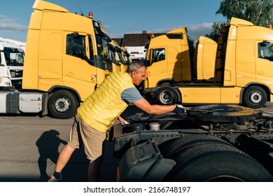 A Worker Smearing Trailer Fifth Wheel Coupling With Lubricant Oil. Semi-truck Mechanical Maintenance 