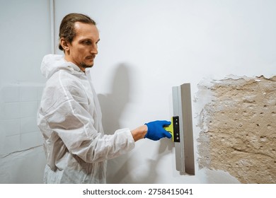 Worker Smooths Plaster Surface Carefully. Applying Metal Trowel To Create Even Wall Finish. Meticulous Application Of Plaster On Walls Using Trowel To Achieve Uniform Surface For Painting