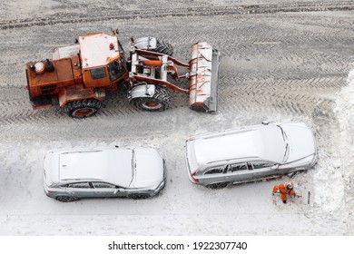 Worker And Snow Plow Machine Removing The Snow On The Parking Lot, Top View. Snowfall In Winter City, Cars Got Stuck