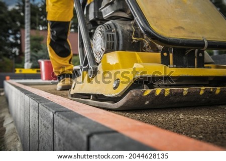Worker with Soil Compactor Preparing Ground For Paving. Heavy Duty Construction Machinery.