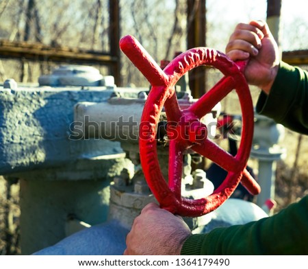 Worker spins the red valve and shuts off the gas supply. Hand and valve ring close-up.