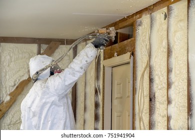 Worker spraying closed cell spray foam insulation on a home that was flooded by Hurricane Harvey
