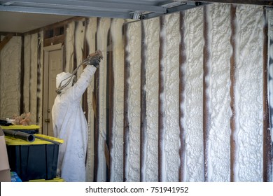 Worker spraying closed cell spray foam insulation on a home that was flooded by Hurricane Harvey
