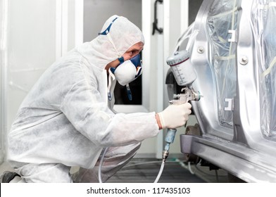 Worker Spraying Grey Paint On A Car In Special Painting Booth