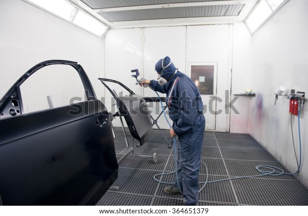 worker spraying paint on car\
parts