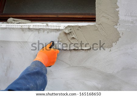 Worker spreading  mortar over styrofoam insulation with trowel