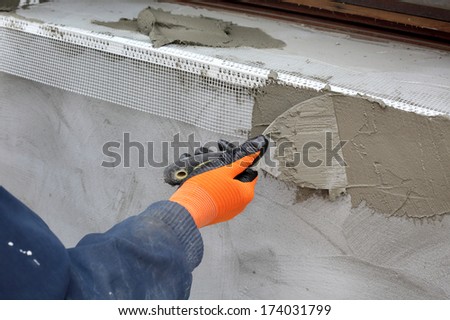 Worker spreading  mortar over styrofoam insulation with trowel