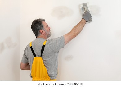 Worker Spreading  Plaster To Wall With Trowel, Repairing Works