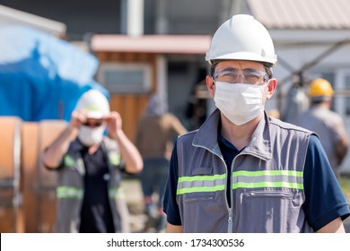 The Worker (staff, Engineer) Protects Himself From Covid-19 (coronavirus) With A Protective Mask In The Construction Site.