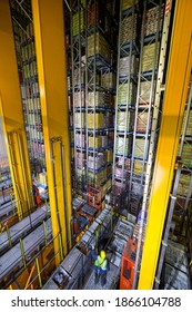 Worker standing below foodstuffs merchandise that is stored in a warehouse with an automated storage and retrieval system - Shutterstock ID 1866104788