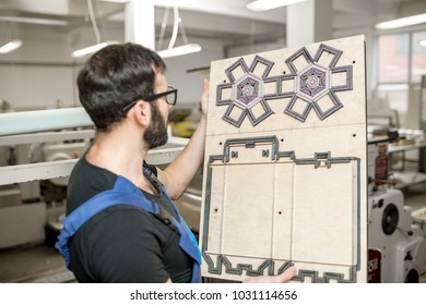 Worker standing with cliche for cutting boxes at the vintage printing manufacturing