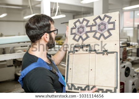 Worker standing with cliche for cutting boxes at the vintage printing manufacturing