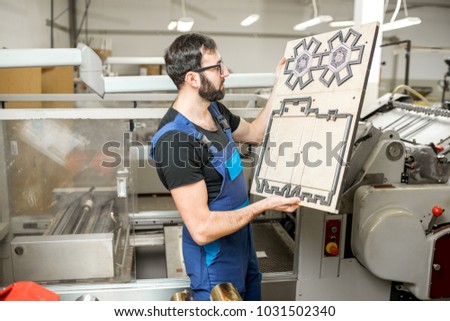 Worker standing with cliche for cutting boxes at the vintage printing manufacturing