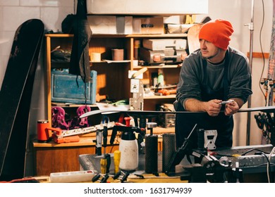 Worker Standing Near Snowboard And Looking Away In Repair Shop