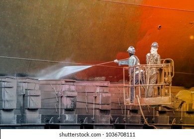 Worker standing on sherry picker car wear equipment safety harness to cleaning column of a ship with high pressure water