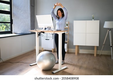 Worker Stretch Exercise At Stand Desk In Office