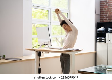 Worker Stretch Exercise At Stand Desk In Office