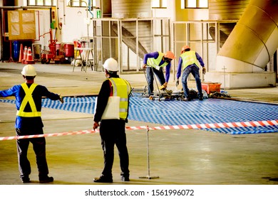Worker stretching the red white warning tape to the pole at construction site.Red and white Hazardous restricted area tape at construction area of factory to mark territory works and worker inside. - Shutterstock ID 1561996072