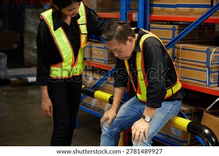 Worker suffering from hard work being assisted by a coworker in warehouse