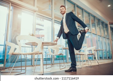 Worker in suit stretching leg at table in office. Stretching at Workplace. - Powered by Shutterstock