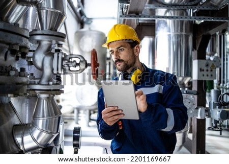 Worker supervisor in district heating plant doing quality control and inspection of pipes and valves.
