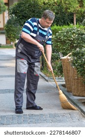 The worker sweeps area around the hotel, provision of cleaning services. - Shutterstock ID 2278146807