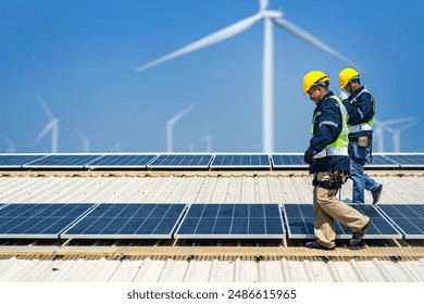 Worker Technicians are working to construct solar panels system on roof with wind turbine on background. Installing solar photovoltaic panel system. Renewable clean energy technology concept. - Powered by Shutterstock