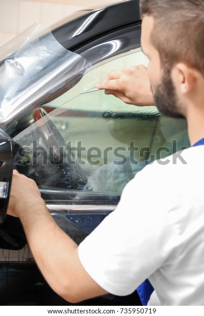 Worker tinting car window in\
shop