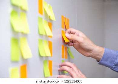 IT worker tracking his tasks on kanban board. Using task control of agile development methodology. Man attaching sticky note to scrum task board in the office - Shutterstock ID 1292514085