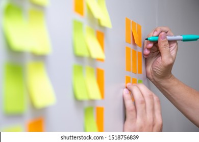 IT worker tracking his tasks on kanban board. Using task control of agile development methodology. Man attaching sticky note to scrum task board in the office - Shutterstock ID 1518756839