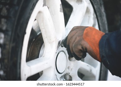 Worker is twisting off a car wheel close up.