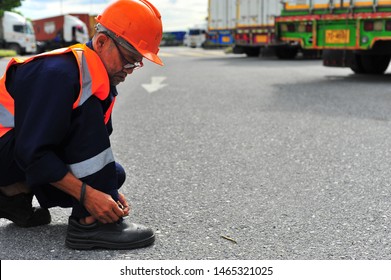 Worker Tying A Safety Shoe In The Parking Lot.