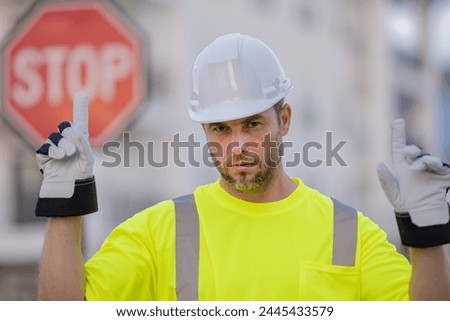 Worker in uniform gesturing stop. Worker builder in hard hat with stop road sign. Builder with stop gesture, no hand, dangerous on building concept. Man in helmet showing stop road sign.