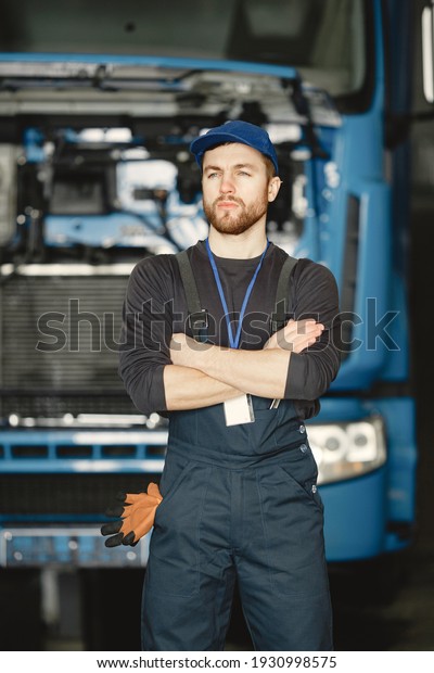 Worker in\
uniform. Man repairs a truck. Man with\
tools