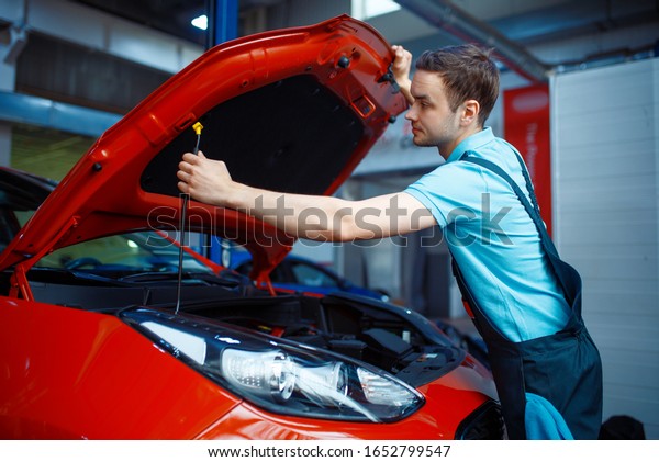 Worker in\
uniform opens vehicle hood, car\
service