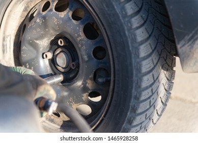 Worker unscrews the screws holding the wheel. Work in tire shop. - Shutterstock ID 1465928258
