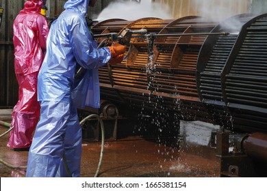 Worker use high pressure water jet to cleaning splashing the dirt of tube bundle in industrial areas, chemical products or oil and gas plants.
