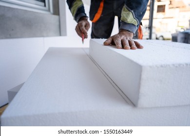 Worker use pen to mark the correct length and dimension of styrofoam during the wall insulation process at the construction site to cut the right size of the board - Powered by Shutterstock