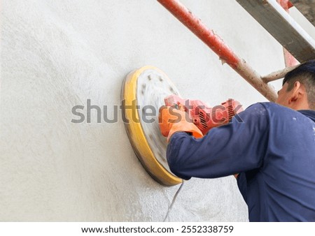 Worker use plaster surface sander on cement wall in new house.