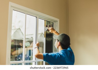 Worker use scraper cleaning window before installing tinting window film.
