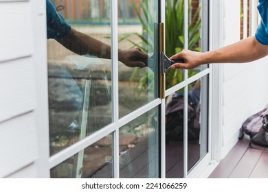 Worker use scraper cleaning window before installing tinting film. - Shutterstock ID 2241066259