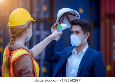 The Worker Used A Medical Digital  Temperature Thermometer To Check Staff Body Temperature Before Start Work In Factory ,they Wearing Face Mask The Concept Of A Corona Virus [Covid-19] Screening.